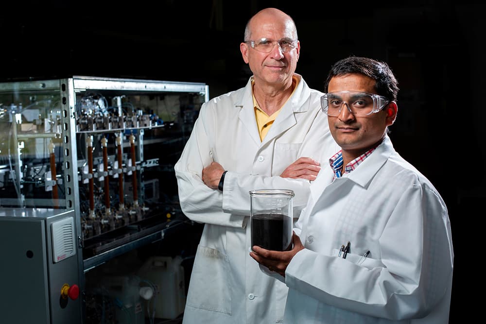 Santanu Bakshi and a colleague in a research lab, holding a sample beaker.